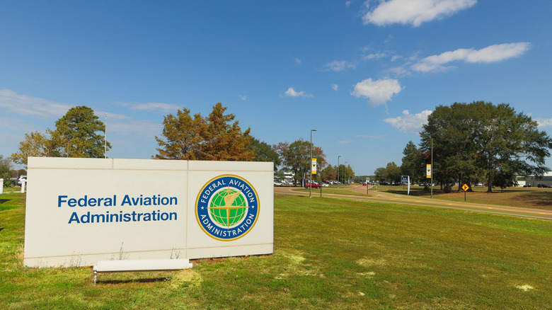 Photo of a sign for the Federal Aviation Administration shown during the daytime. Sign is placed on a green lawn and blue sky.